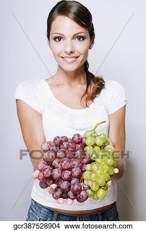 Picture - Portrait of a woman holding green and red grapes. Fotosearch