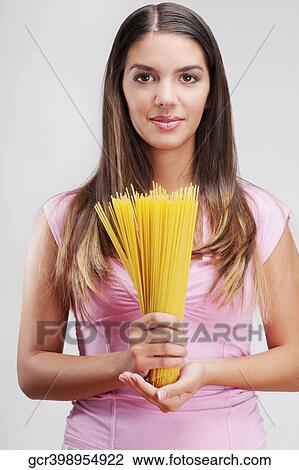 Stock Image - Portrait of a woman holding uncooked spaghetti. Fotosearch