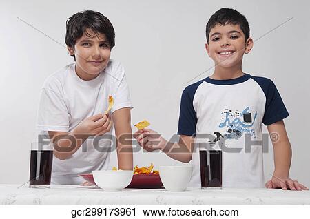 Portrait of two boys eating nachos View Large Photo Image Stock Image - Portrait of two boys eating nachos. Fotosearch