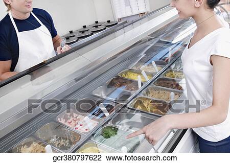 Sales clerk attending a customer in an ice cream parlor View Large Photo Image Stock Image - Sales clerk attending a customer in an ice cream parlor. Fotosearch