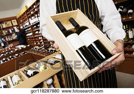 Stock Image - Sales clerk showing a crate of wine bottles. Fotosearch