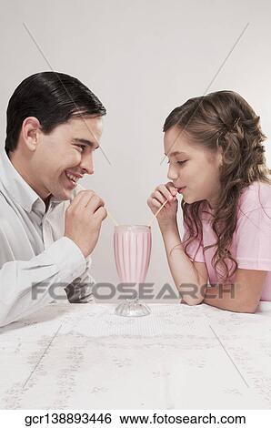 Stock Photograph - Side profile of a father and daughter sharing a milkshake. Fotosearch
