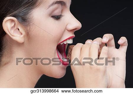 Side profile of a woman eating a brownie View Large Photo Image Picture - Side profile of a woman eating a brownie. Fotosearch