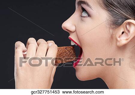 Side profile of a woman eating a brownie View Large Photo Image Stock Image - Side profile of a woman eating a brownie. Fotosearch