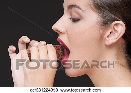 Side profile of a woman eating a brownie View Large Photo Image Stock Photo - Side profile of a woman eating a brownie. Fotosearch