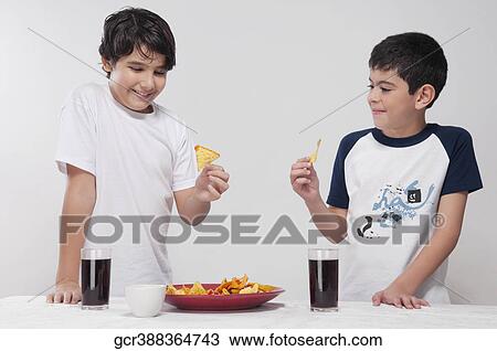 Two boys eating nachos from a platter View Large Photo Image Stock Image - Two boys eating nachos from a platter. Fotosearch