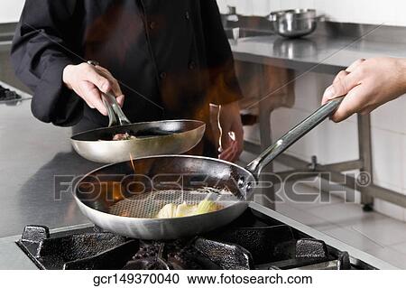 Stock Image - Two chefs cooking food in the kitchen. Fotosearch