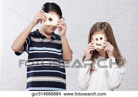 Two children hiding their faces with slices of bread View Large Photo Image Picture - Two children hiding their faces with slices of bread. Fotosearch