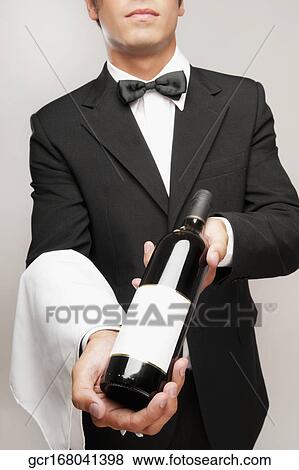 Waiter holding a bottle of wine View Large Photo Image Stock Photo - Waiter holding a bottle of wine. Fotosearch