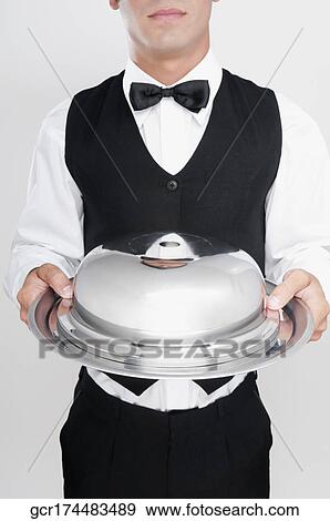 Waiter holding a covered dish View Large Photo Image Stock Photo - Waiter holding a covered dish. Fotosearch