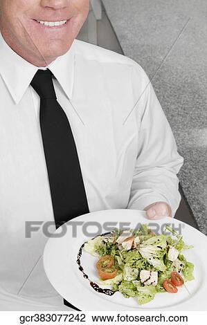 Waiter holding a plate of vegetable salad View Large Photo Image Stock Image - Waiter holding a plate of vegetable salad. Fotosearch