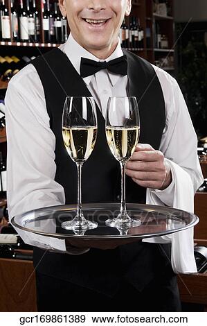 Waiter holding a tray of champagne flutes View Large Photo Image Stock Photo - Waiter holding a tray of champagne flutes. Fotosearch