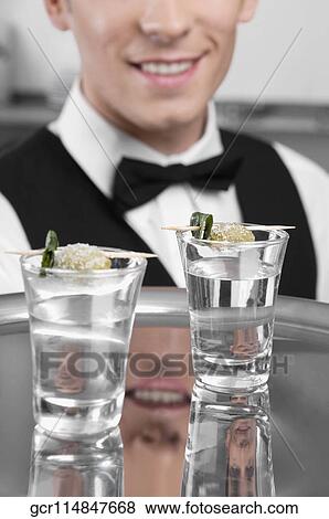 Stock Photo - Waiter holding a tray of tequila shots. Fotosearch