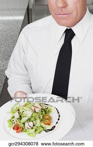 Waiter holding vegetable salad in plate View Large Photo Image Stock Photo - Waiter holding vegetable salad in plate. Fotosearch