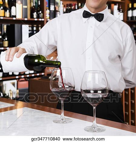 Stock Image - Waiter pouring wine into a glass. Fotosearch