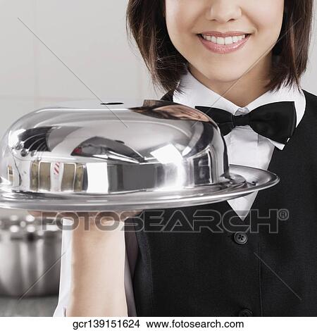 Picture - Waitress holding a domed tray. Fotosearch