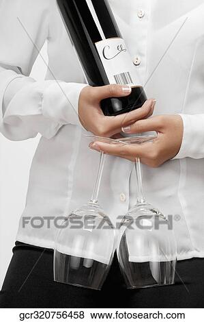 Stock Photo - Waitress holding a wine bottle and wine glasses. Fotosearch