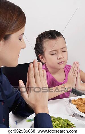 Woman and her daughter praying before lunch View Large Photo Image Stock Photo - Woman and her daughter praying before lunch. Fotosearch