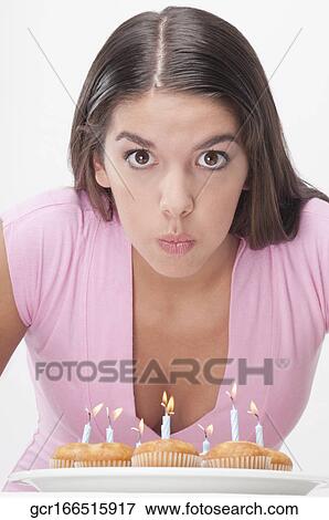 Woman blowing out candles on cupcakes View Large Photo Image Stock Photo - Woman blowing out candles on cupcakes. Fotosearch