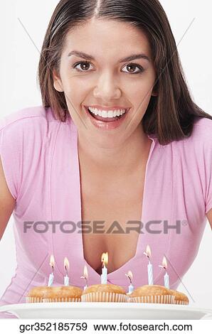 Woman blowing out candles on cupcakes View Large Photo Image Stock Photo - Woman blowing out candles on cupcakes. Fotosearch