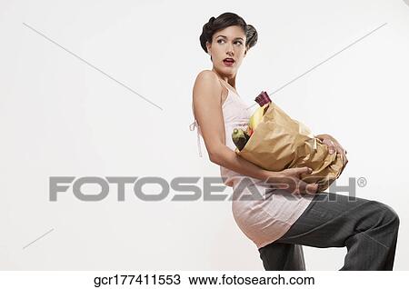 Stock Image - Woman carrying a bag of vegetables. Fotosearch
