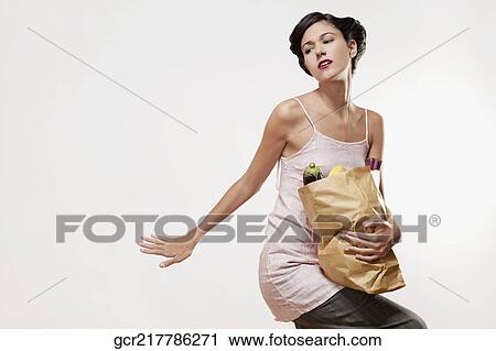 Stock Image - Woman carrying a bag of vegetables. Fotosearch