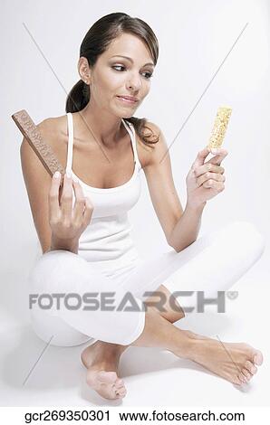 Woman choosing between a chocolate and a protein bar View Large Photo Image Stock Image - Woman choosing between a chocolate and a protein bar. Fotosearch