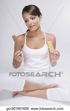 Woman choosing between a chocolate and a protein bar View Large Photo Image Stock Photograph - Woman choosing between a chocolate and a protein bar. Fotosearch