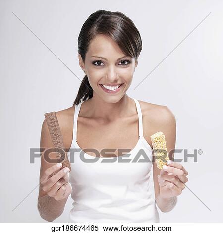 Woman choosing between a chocolate and a protein bar View Large Photo Image Stock Photography - Woman choosing between a chocolate and a protein bar. Fotosearch