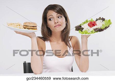 Woman choosing between a hamburger plate and a salad plate View Large Photo Image Stock Photo - Woman choosing between a hamburger plate and a salad plate. Fotosearch