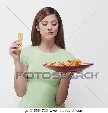 Woman choosing between a protein bar and a platter of nachos View Large Photo Image Stock Image - Woman choosing between a protein bar and a platter of nachos. Fotosearch