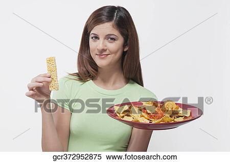 Woman choosing between a protein bar and a platter of nachos View Large Photo Image Stock Photography - Woman choosing between a protein bar and a platter of nachos. Fotosearch