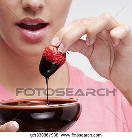 Woman dipping a strawberry in chocolate sauce View Large Photo Image Stock Photo - Woman dipping a strawberry in chocolate sauce. Fotosearch