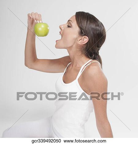 Stock Image - Woman eating a green apple. Fotosearch