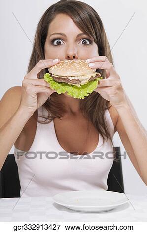Woman eating a hamburger View Large Photo Image Stock Photo - Woman eating a hamburger. Fotosearch