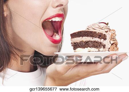 Woman eating a pastry on a plate View Large Photo Image Stock Photo - Woman eating a pastry on a plate. Fotosearch