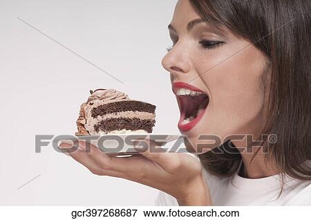 Woman eating a pastry on a plate View Large Photo Image Stock Photo - Woman eating a pastry on a plate. Fotosearch