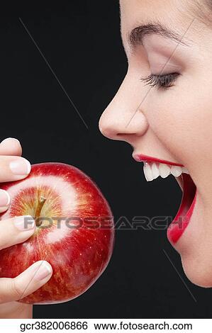 Woman eating a red apple and smiling View Large Photo Image Stock Photograph - Woman eating a red apple and smiling. Fotosearch
