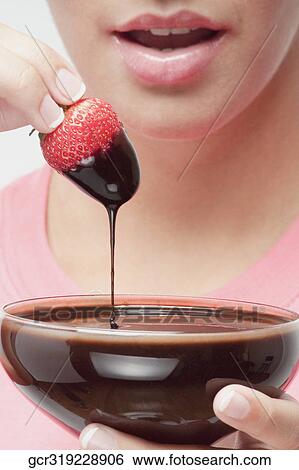 Woman eating a strawberry dipped in chocolate sauce View Large Photo Image Stock Photograph - Woman eating a strawberry dipped in chocolate sauce. Fotosearch
