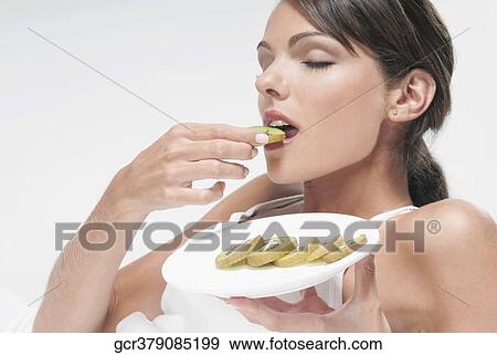 Woman eating sliced kiwi fruit View Large Photo Image Stock Photo - Woman eating sliced kiwi fruit. Fotosearch