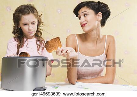 Woman giving her daughter a piece of burnt toast View Large Photo Image Stock Photo - Woman giving her daughter a piece of burnt toast. Fotosearch