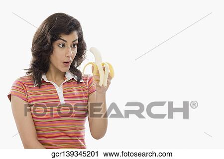 Woman holding a banana and looking surprised View Large Photo Image Stock Image - Woman holding a banana and looking surprised. Fotosearch