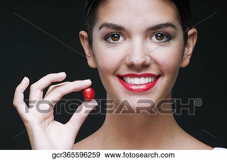 Woman holding a cherry tomato and smiling View Large Photo Image Stock Photo - Woman holding a cherry tomato and smiling. Fotosearch