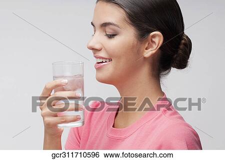 Woman holding a glass of water and smiling View Large Photo Image Stock Photograph - Woman holding a glass of water and smiling. Fotosearch