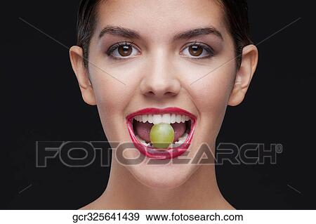 Woman holding a green grape between her teeth View Large Photo Image Stock Photo - Woman holding a green grape between her teeth. Fotosearch