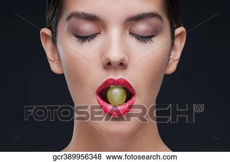 Woman holding a green grape between her teeth View Large Photo Image Stock Photo - Woman holding a green grape between her teeth. Fotosearch