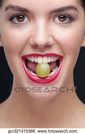 Woman holding a green grape between her teeth View Large Photo Image Stock Photograph - Woman holding a green grape between her teeth. Fotosearch