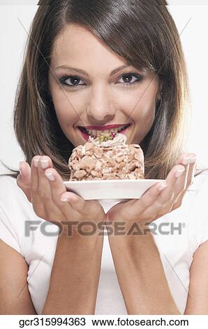 Stock Image - Woman holding a pastry on a plate. Fotosearch