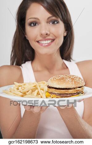 Stock Image - Woman holding a plate of hamburger and fries. Fotosearch