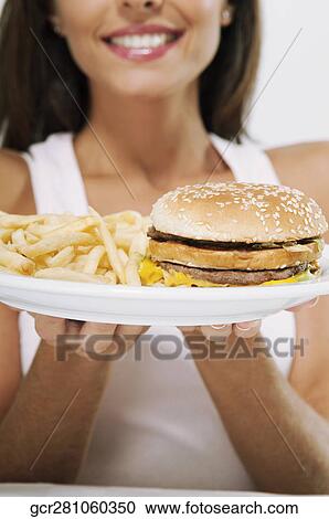 Woman holding a plate of hamburger and fries View Large Photo Image Stock Image - Woman holding a plate of hamburger and fries. Fotosearch